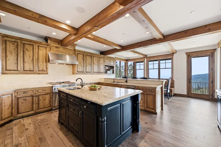 Exposed wood beams, wood-finish flooring, custom wood cabinetry, granite countertops, and a professional-grade range with a stainless steel hood