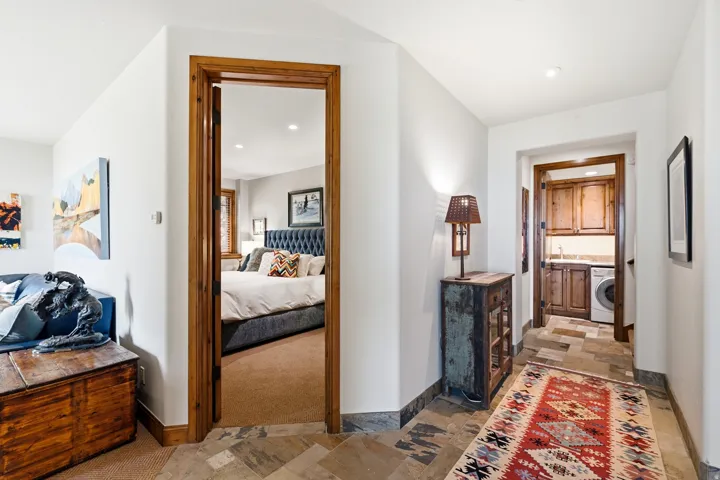 Hardwood door frames and baseboards, stone flooring, built-in cabinetry, integrated sink, and a front-loading washing machine