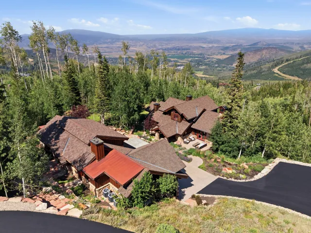 Extensive property featuring multiple structures with complementary roofing, surrounded by mature trees