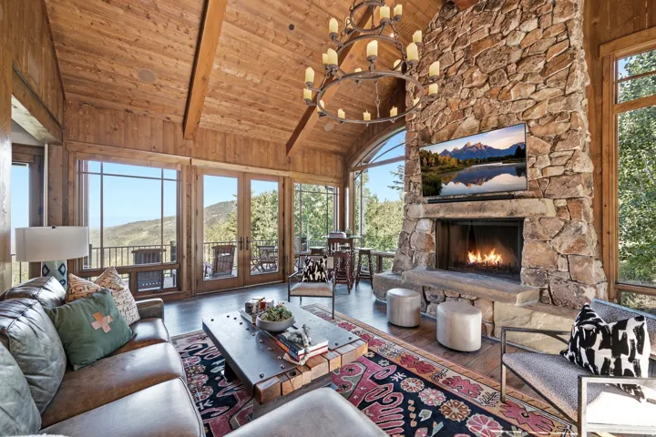 Vaulted wood-paneled ceiling with exposed beams, stone fireplace, and wood-finish flooring
