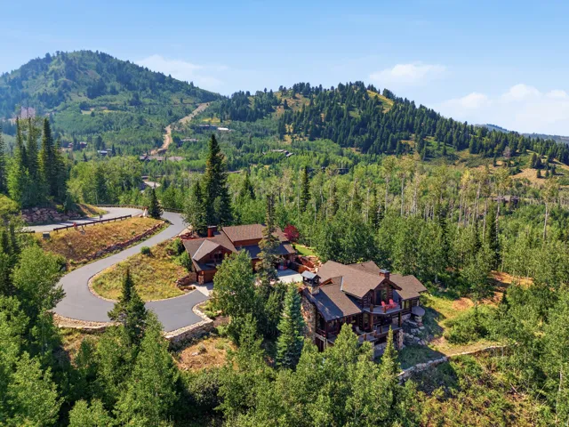 Paved driveway leading to a multi-level residence with extensive landscaping