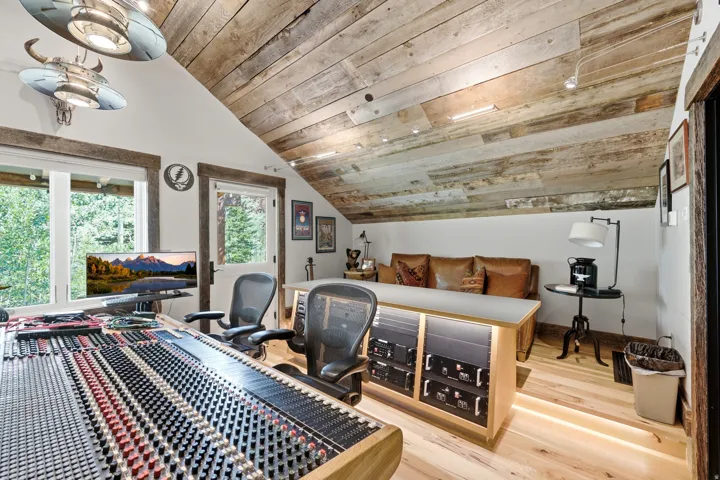 Vaulted ceiling with wood paneling, wood-finish flooring, built-in desk with integrated lighting, and dual windows