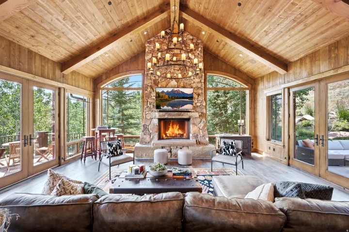 Vaulted wood-paneled ceilings, a stone-clad fireplace, and expansive floor-to-ceiling windows