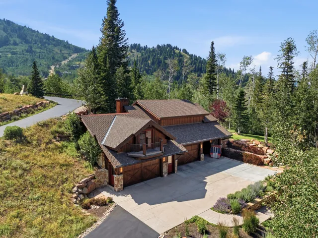 Wood siding exterior with stone accents, an attached two-car garage, an additional attached single-car garage, and a large paved driveway