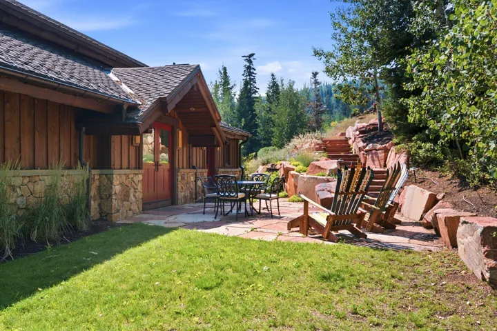 Wood-sided exterior with stone foundation accents, shingle roof, flagstone patio, and terraced landscaping with stone steps