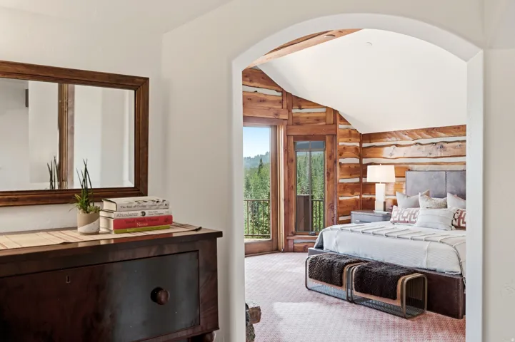 Arched doorway revealing a spacious room with log walls and a vaulted ceiling