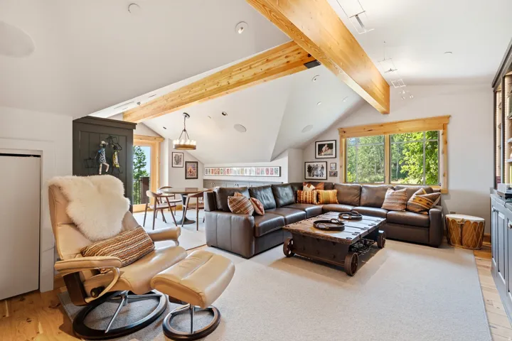 Vaulted ceiling with exposed wood beams, large window with wood trim, wood-finish flooring, recessed lighting, and a built-in cabinet