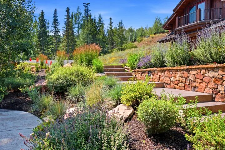 Tiered landscaping with natural stone retaining walls, integrated steps, and varied plantings