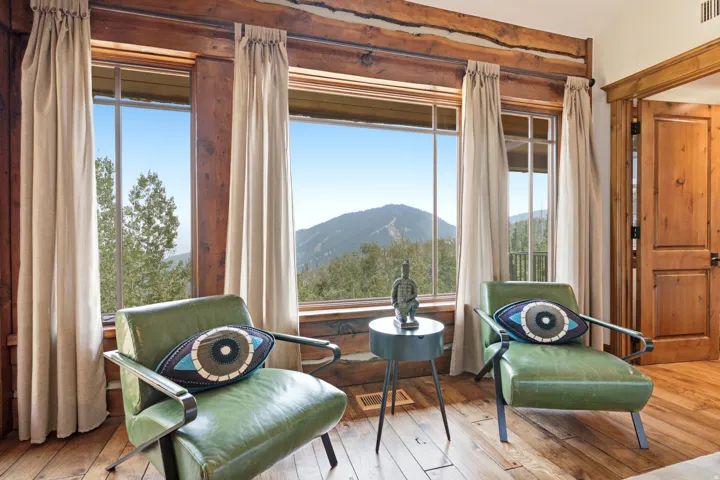 Expansive windows with mountain scenery, rich wood-finish flooring, and natural wood-beam accents