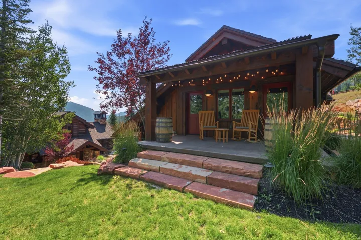 Expansive exterior with a covered porch, stone steps, and a manicured lawn