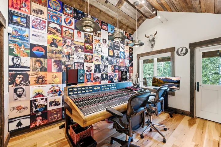Vaulted wood-plank ceiling, wood-finish flooring, two large windows, white paneled door with dark hardware, and rustic wood trim