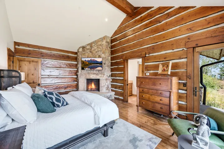 Wood-finish flooring, exposed wood beam ceiling, stone fireplace, and log wall finishes