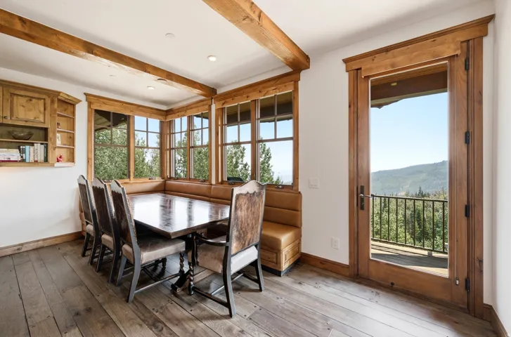 Exposed wood beams and trim, built-in shelving, wood-finish flooring, and a glass-paneled door