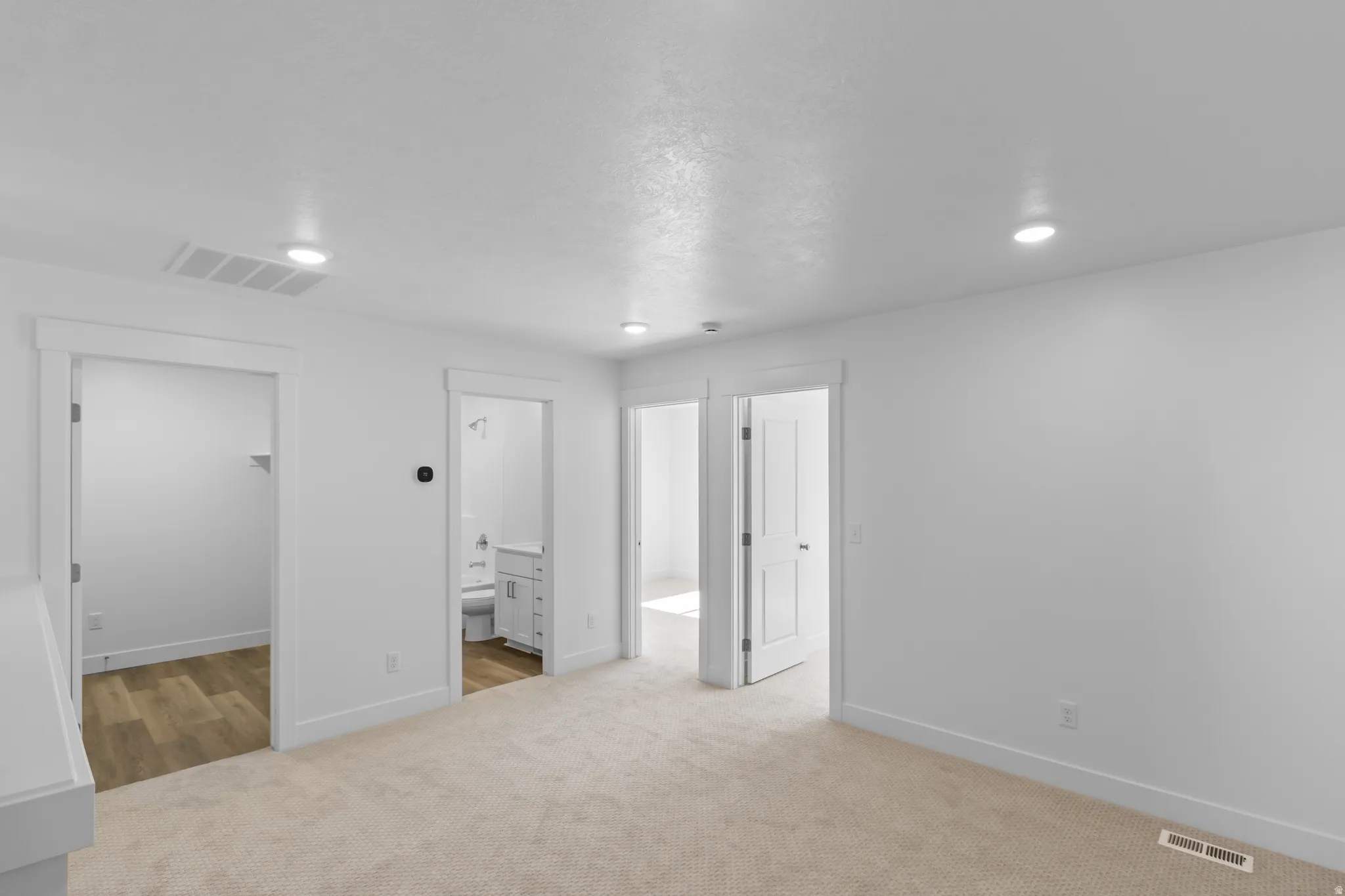 Neutral-toned carpet flooring, recessed ceiling lighting, white walls, white trim, and a white interior door