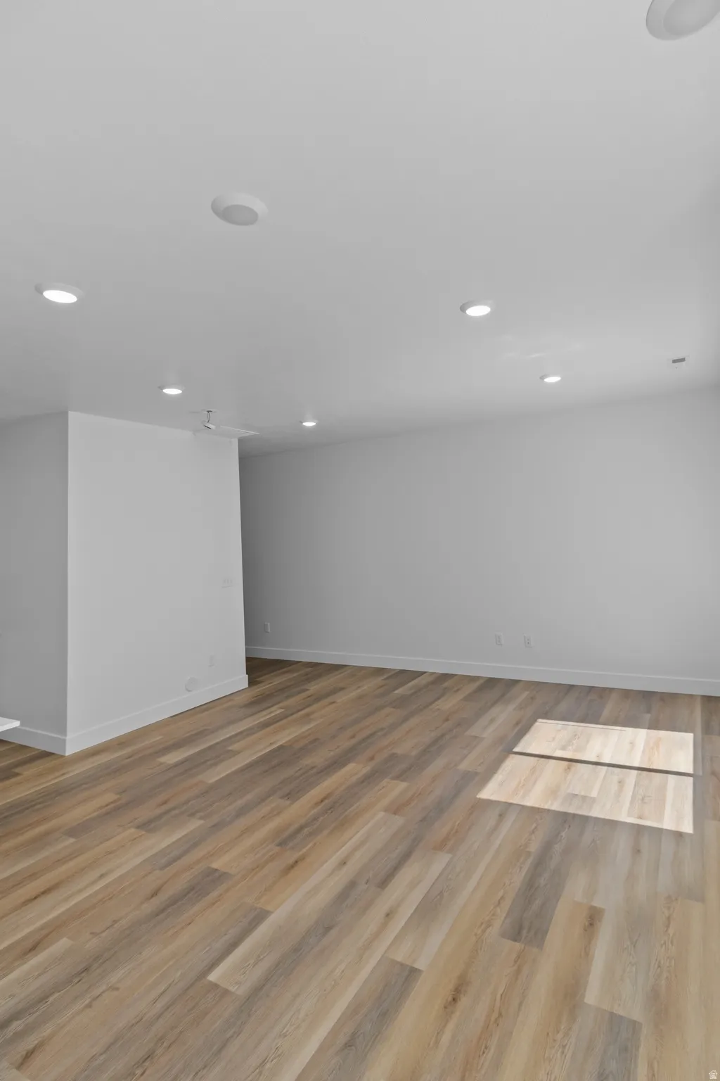 Recessed ceiling lights, wood-finish flooring, white baseboards, and painted walls