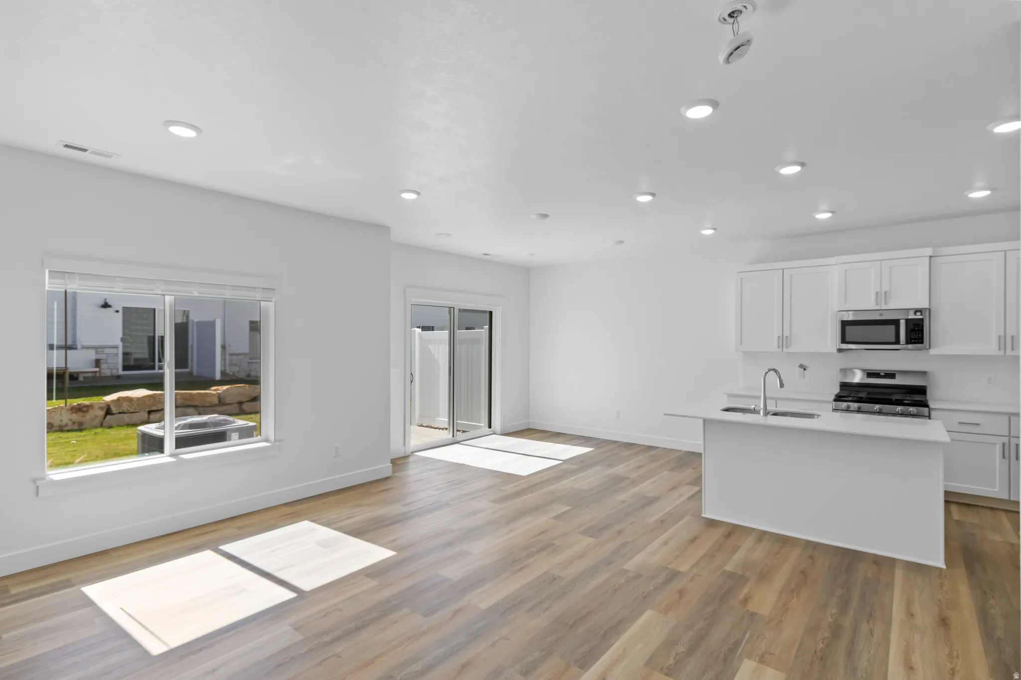 Modern kitchen featuring white cabinetry, a kitchen island with a stainless steel sink, and stainless steel appliances