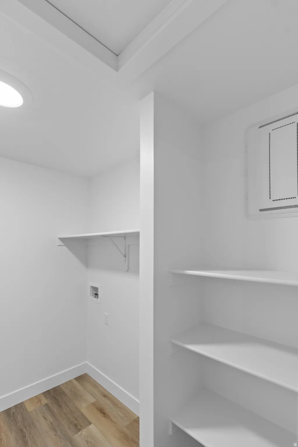 Integrated shelving, wood-finish flooring, recessed lighting, and wall-mounted utility connections