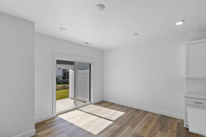 Wood-finish flooring, recessed lighting, sliding glass door, white cabinetry, and a private patio