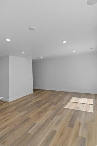 Recessed ceiling lights, wood-finish flooring, white baseboards, and painted walls