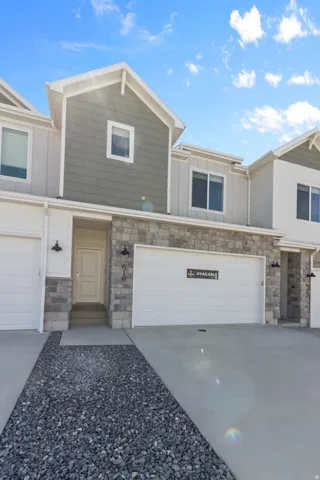 Contemporary townhouse exterior featuring a neutral color palette, stone accents, horizontal siding, and a two-car garage