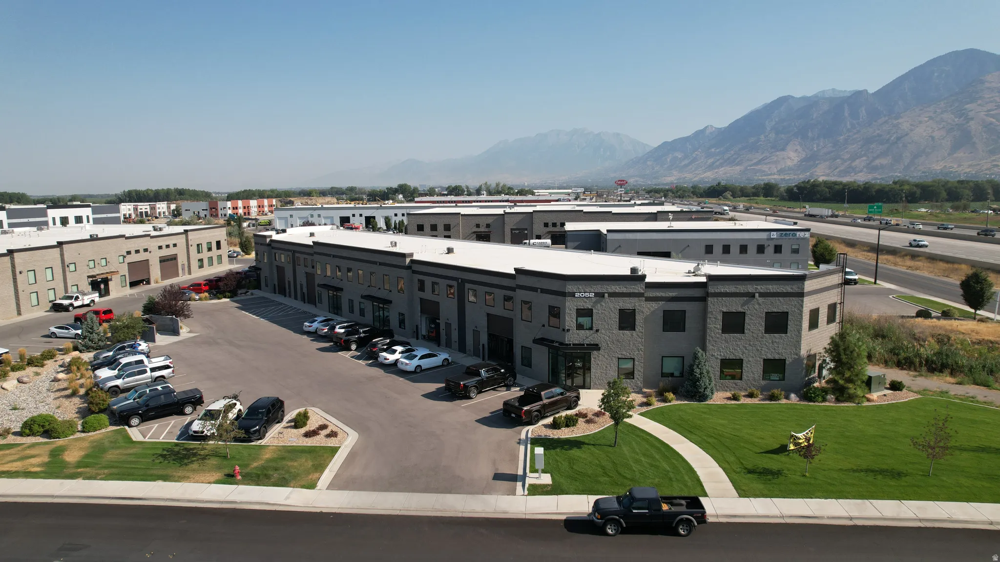 Multi-unit commercial building with stone facade, dark-framed windows, and ample paved parking