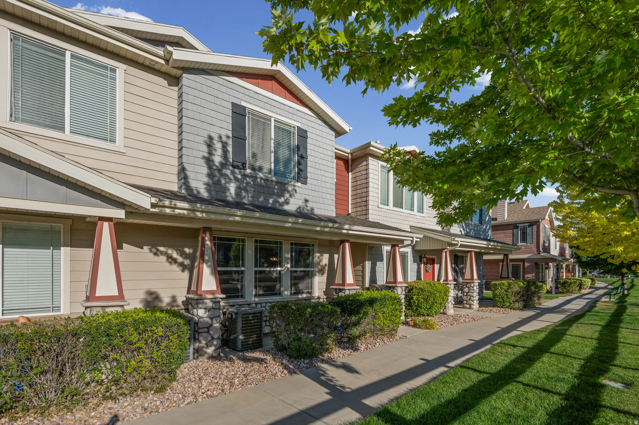 Townhome exterior featuring varied siding materials, stone column bases, and mature landscaping