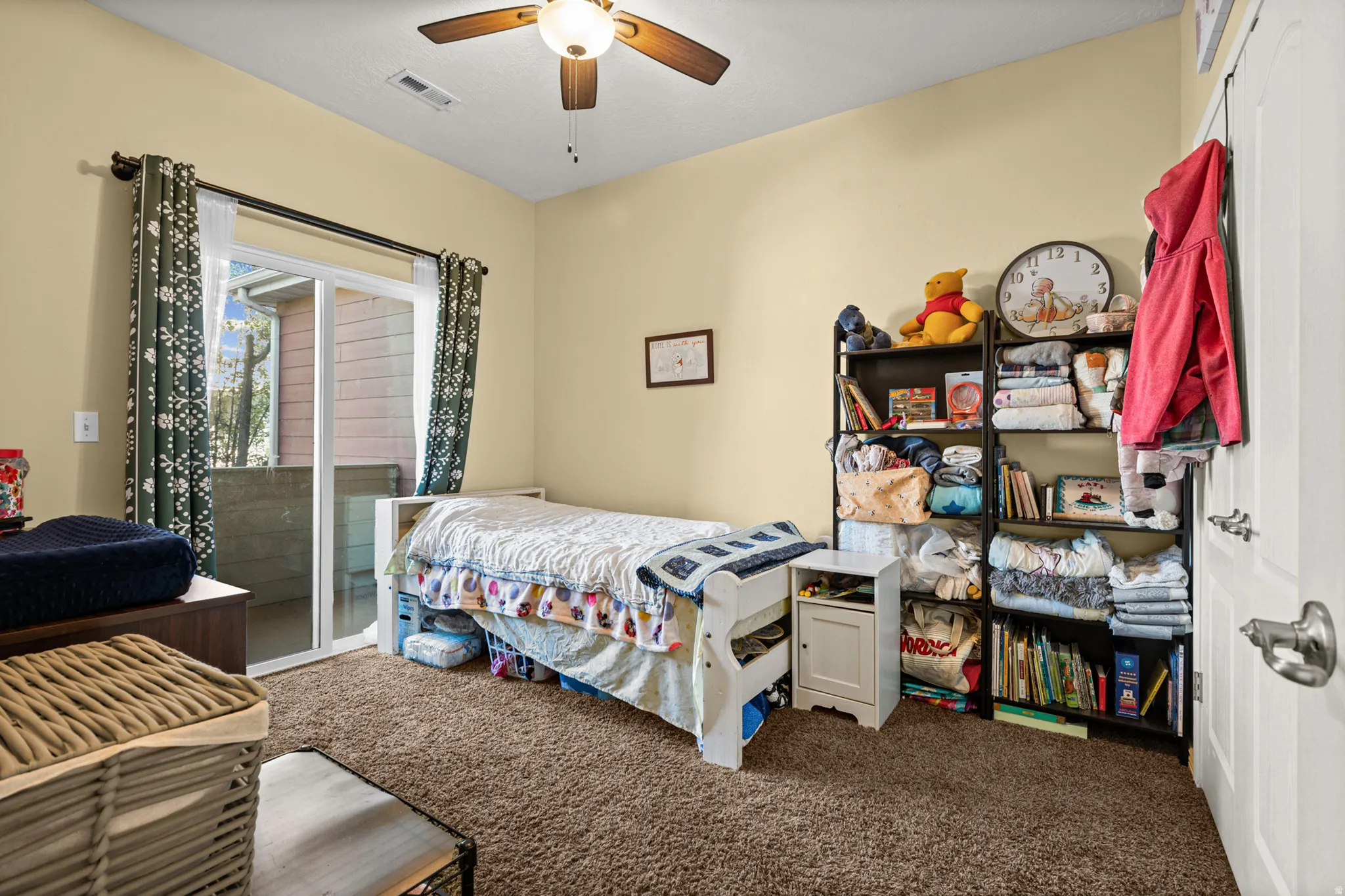 Room with tan walls, brown carpet, and a ceiling fan with light fixture