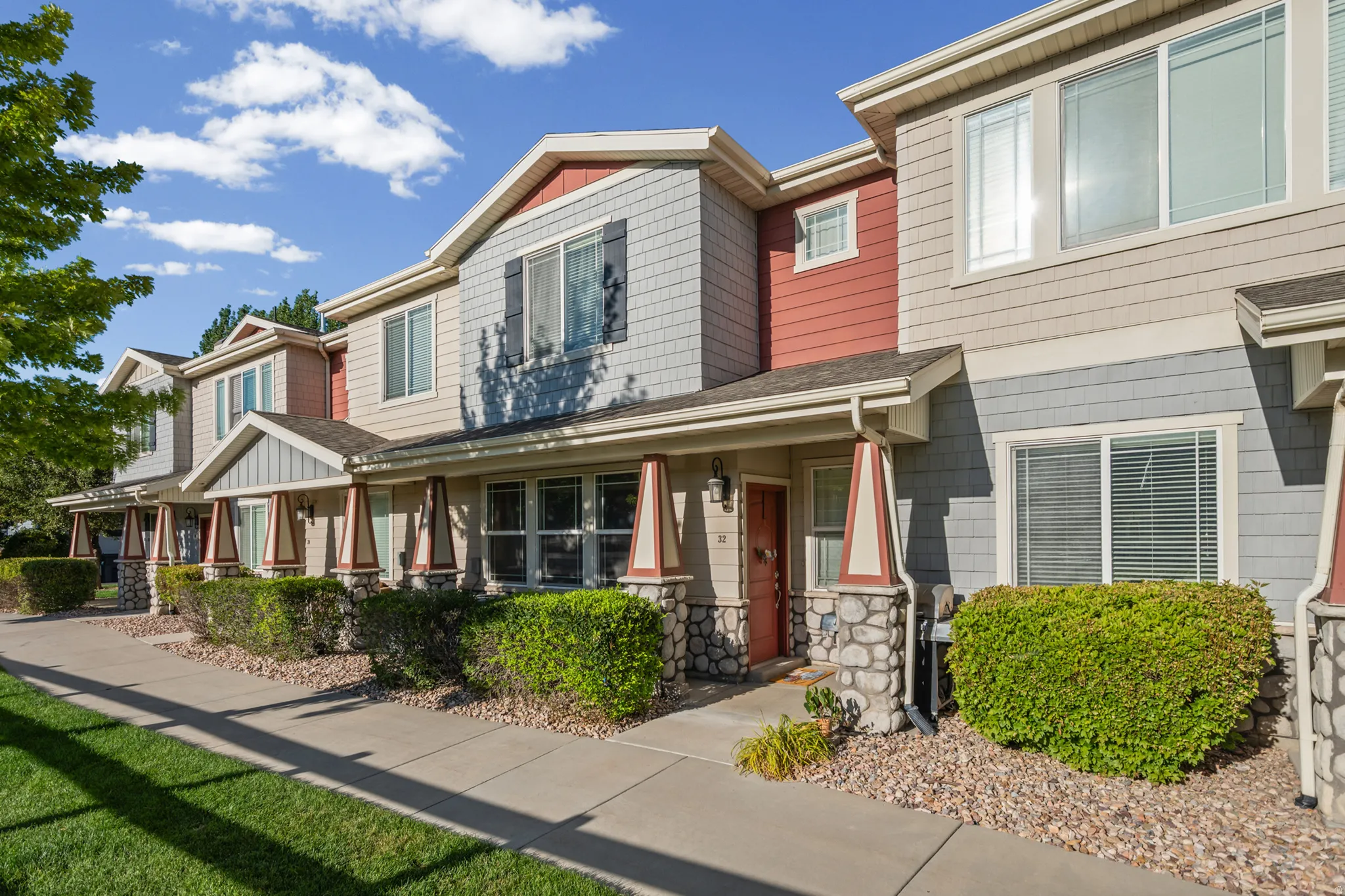 Multi-level townhome exterior featuring varied siding materials, stone accents, and covered entryways