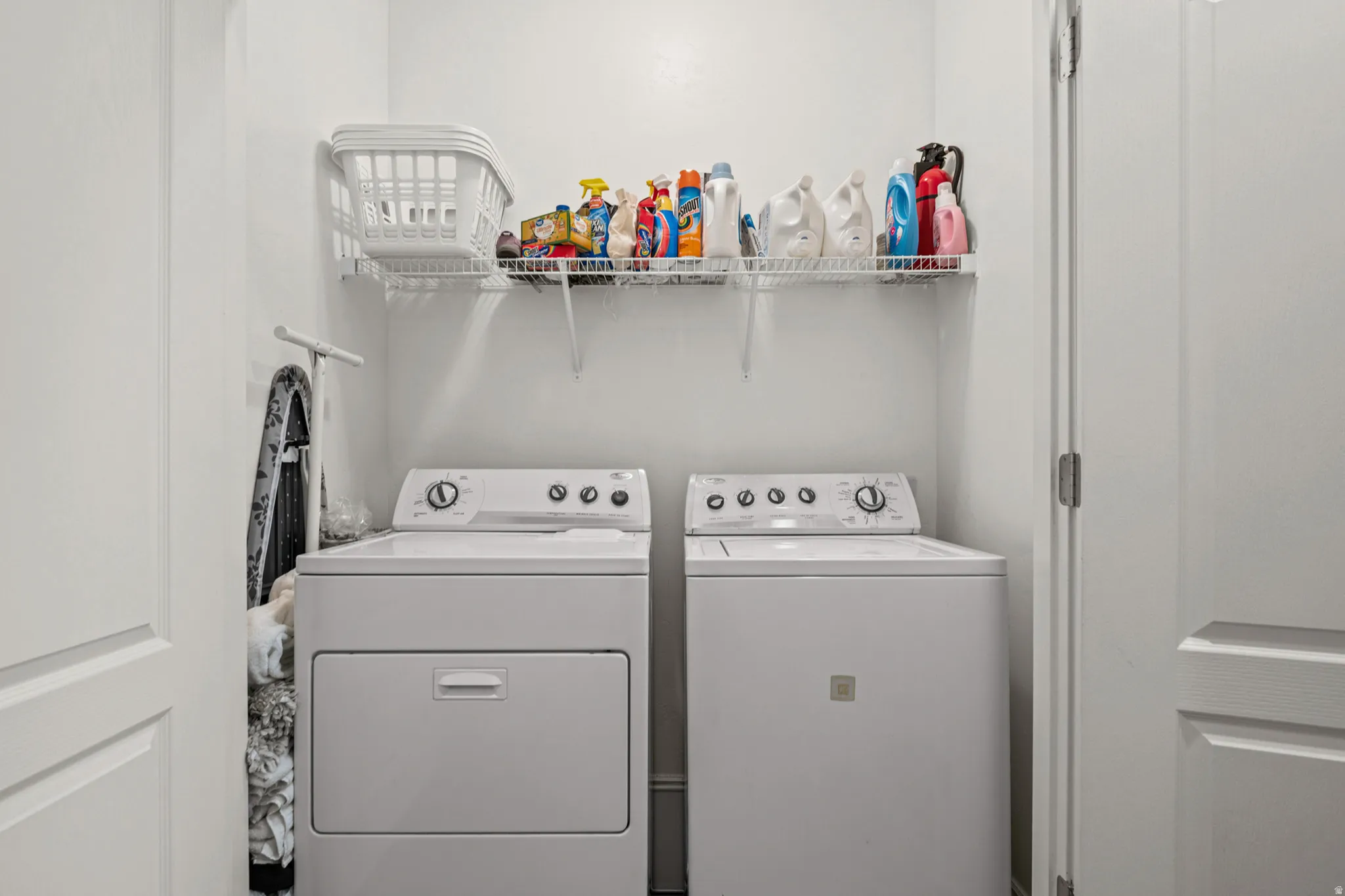 Dedicated laundry area with white walls and a wire shelf