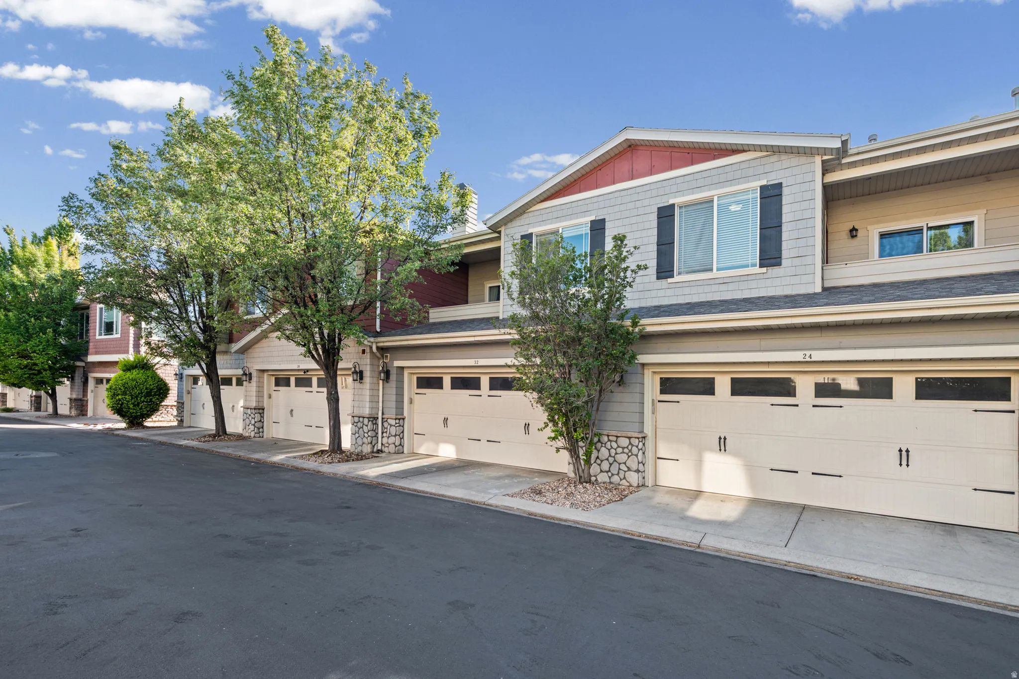 Two-story townhome with light-toned siding and red accent gables