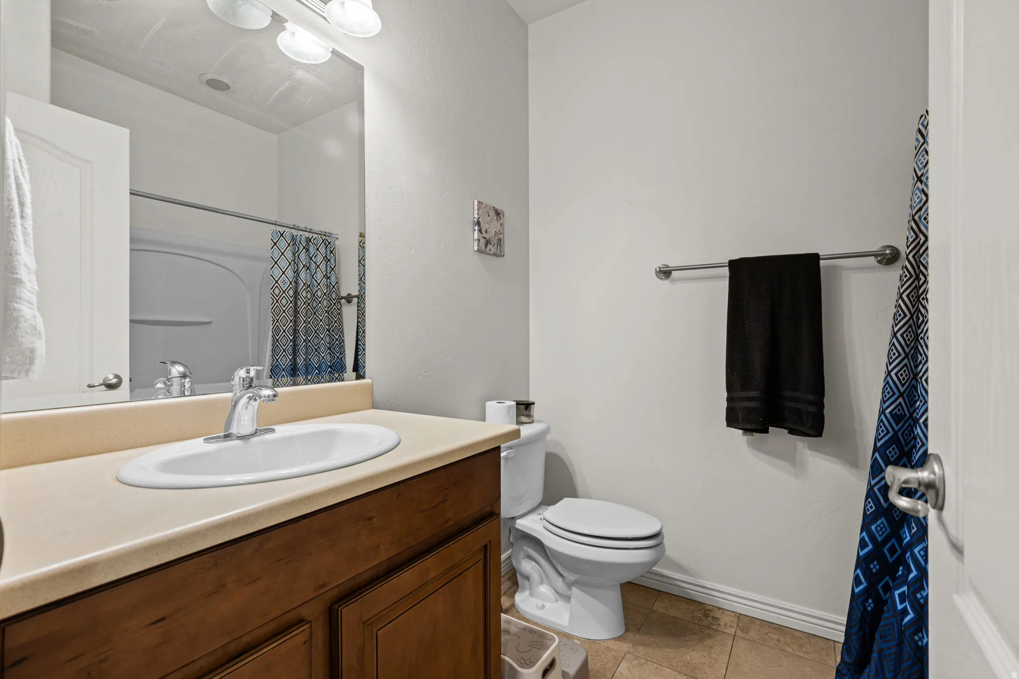 Bathroom featuring a single vanity with an integrated sink, a light-toned countertop, and wood-finish cabinetry
