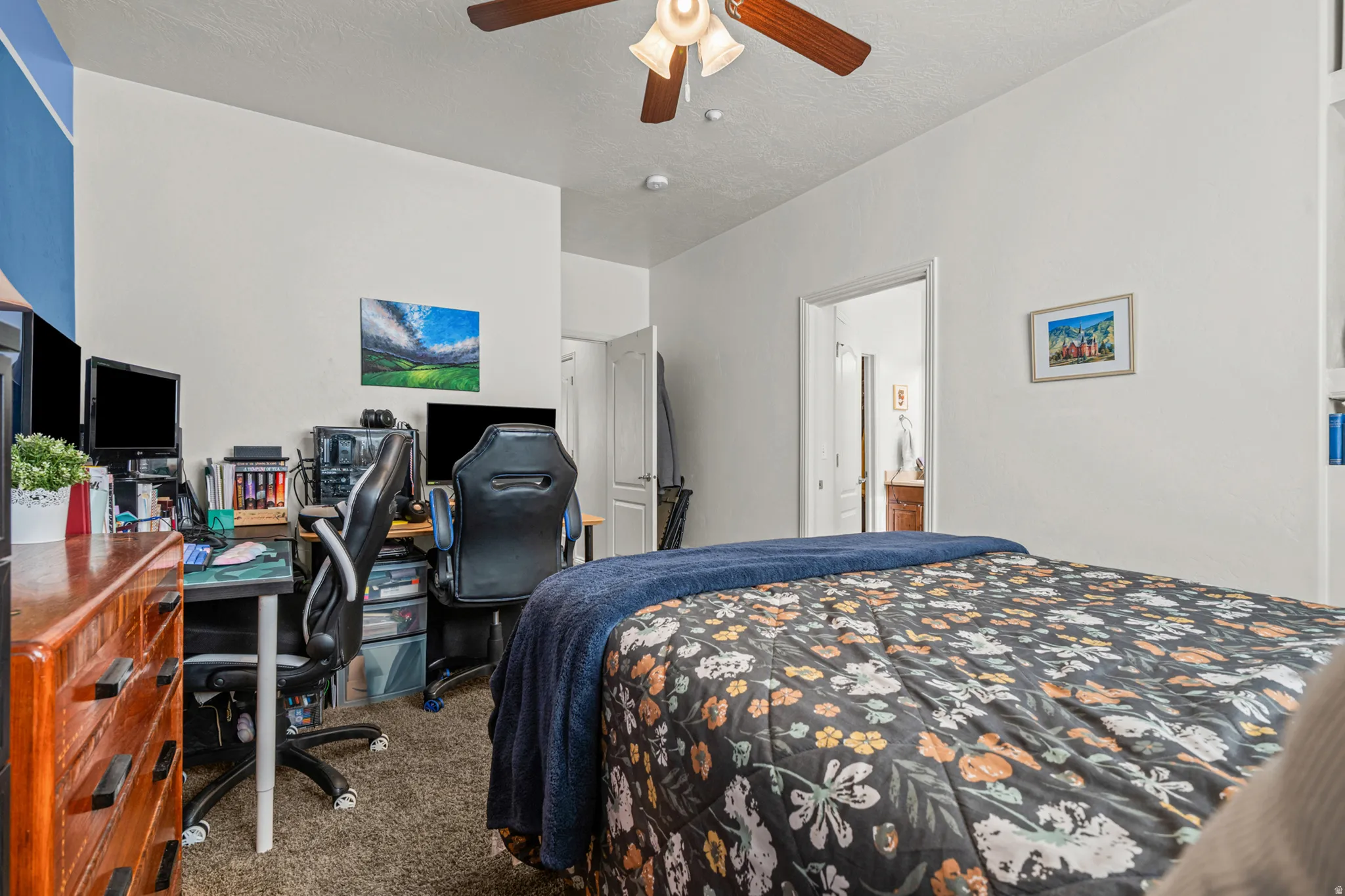 Bedroom featuring neutral wall colors, textured carpet flooring, an overhead ceiling fan with light fixture, and a white interior door