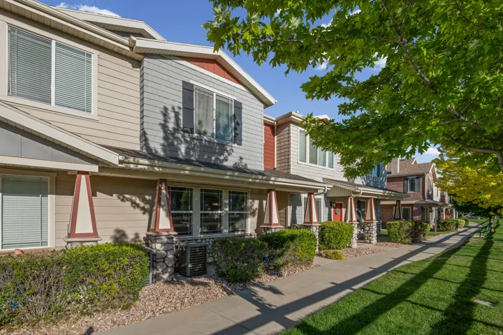 Townhome exterior featuring varied siding materials, stone column bases, and mature landscaping