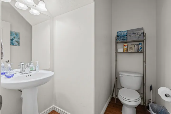 Pedestal sink with chrome faucet, mirror, and multi-bulb vanity lighting
