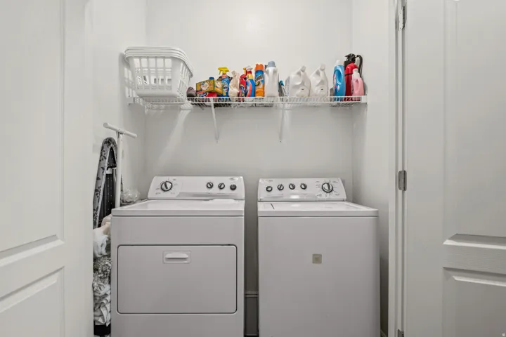 Dedicated laundry area with white walls and a wire shelf