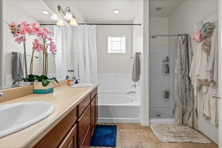 Bathroom featuring a double vanity with integrated sinks, a combination shower-tub, and a separate standing shower