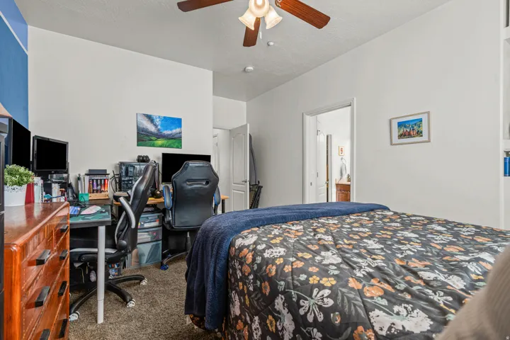 Bedroom featuring neutral wall colors, textured carpet flooring, an overhead ceiling fan with light fixture, and a white interior door