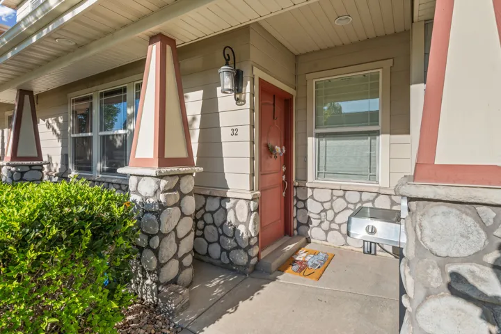 Inviting front entry featuring a paneled door, stone-clad pillars, and exterior wall sconce
