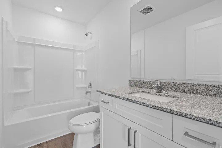 White vanity with chrome hardware, granite-style countertop, and integrated sink
