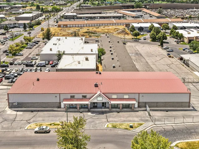 Expansive commercial building with a red roof, a stone-finish facade, and a paved parking lot