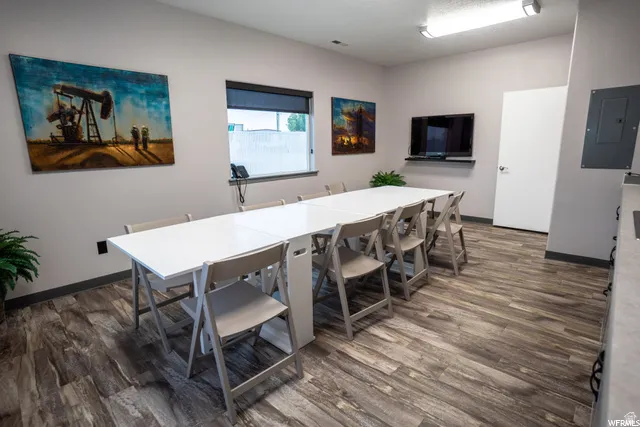 Wood-finish flooring with a neutral wall color, recessed window with dark roller shade, and overhead fluorescent lighting