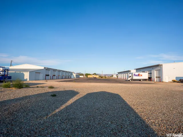 Multiple large industrial buildings with roll-up doors and gravel lot