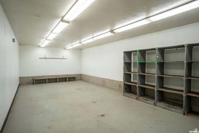 Concrete flooring, fluorescent ceiling lighting, white paneling, built-in shelving, and wood benches