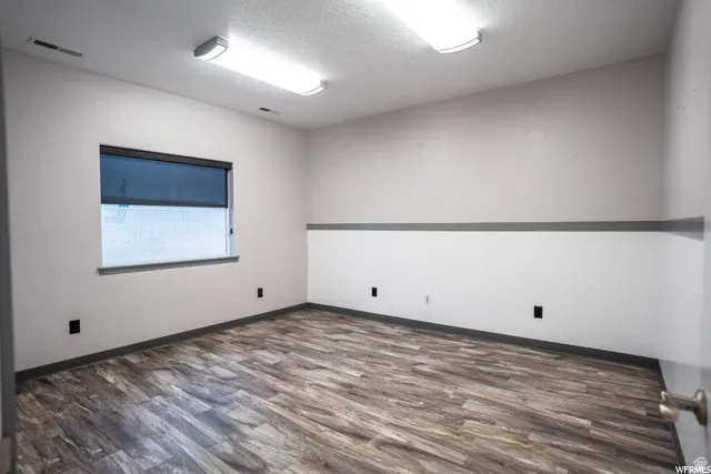 Wood-finish flooring, recessed lighting, and a window with a roller shade