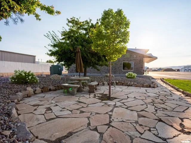 Flagstone patio with a stone picnic table and benches, surrounded by landscaping rock and mature trees