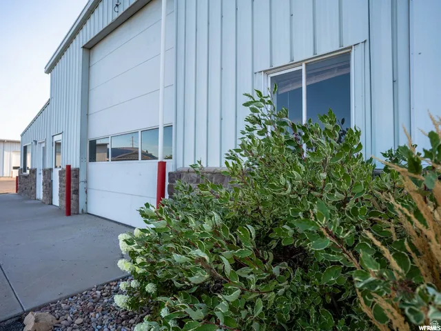 Corrugated metal siding with stone veneer accents, large overhead door with integrated window panels, and a concrete approach