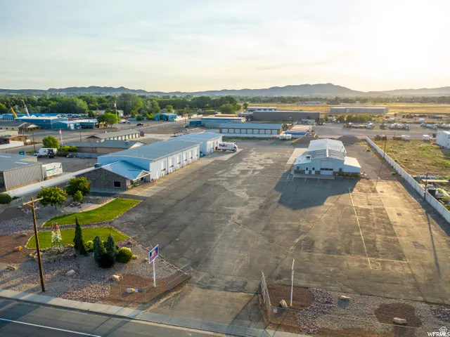 Expansive paved lot with multiple industrial buildings, featuring a landscaped entrance area