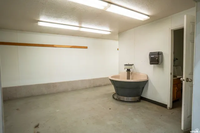 Concrete flooring with strip lighting, wall-mounted fixture, and interior door access