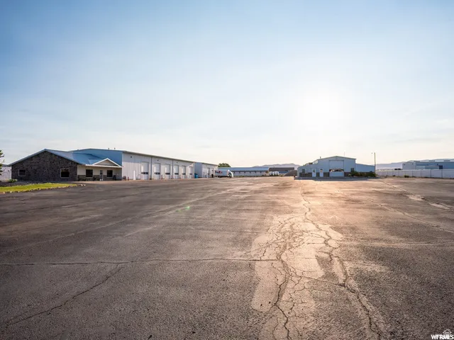 Extensive paved lot with multiple industrial buildings, featuring a building with stone facade and a series of overhead doors