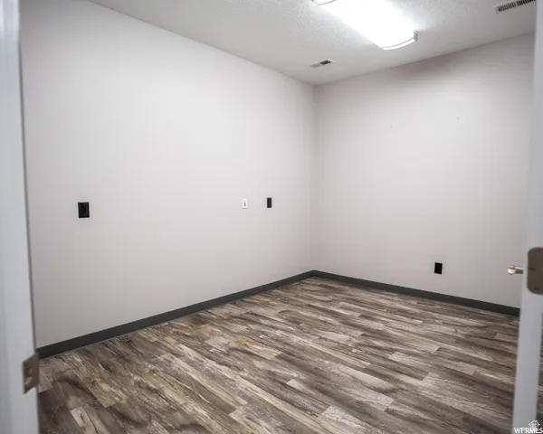Wood-finish flooring, white painted walls, and a semi-flush ceiling light fixture